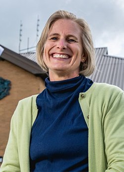 A small card image of Dr Caroline Watson standing outside her general practice wearing a light green cardigan.