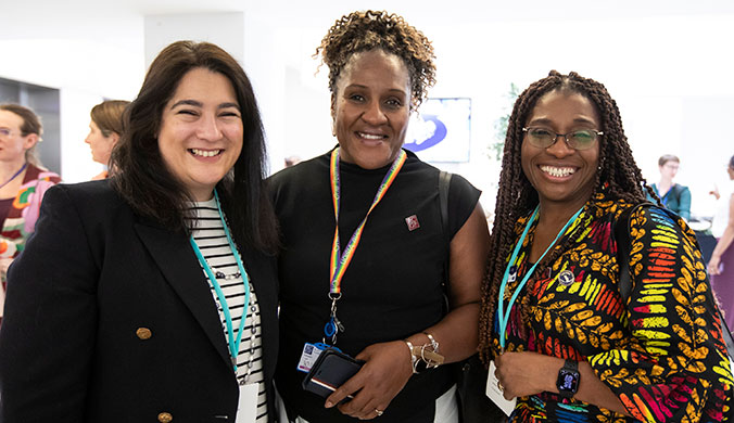 Three women standing and smiling. 
