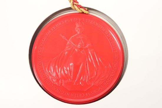 Round red wax seal, showing an image of a person in flowing robes, wearing a crown and holding a sceptre