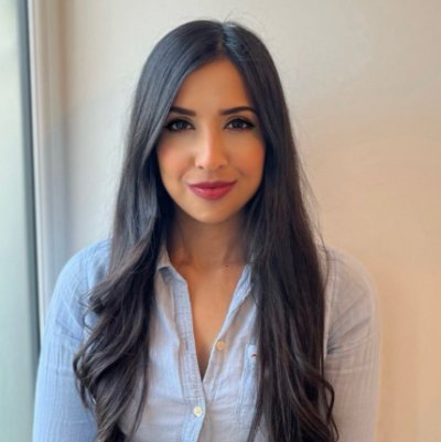 A square head and shoulders image of Dr. Aneeqa Sharif wearing a light blue cotton shirt and her dark hair long.