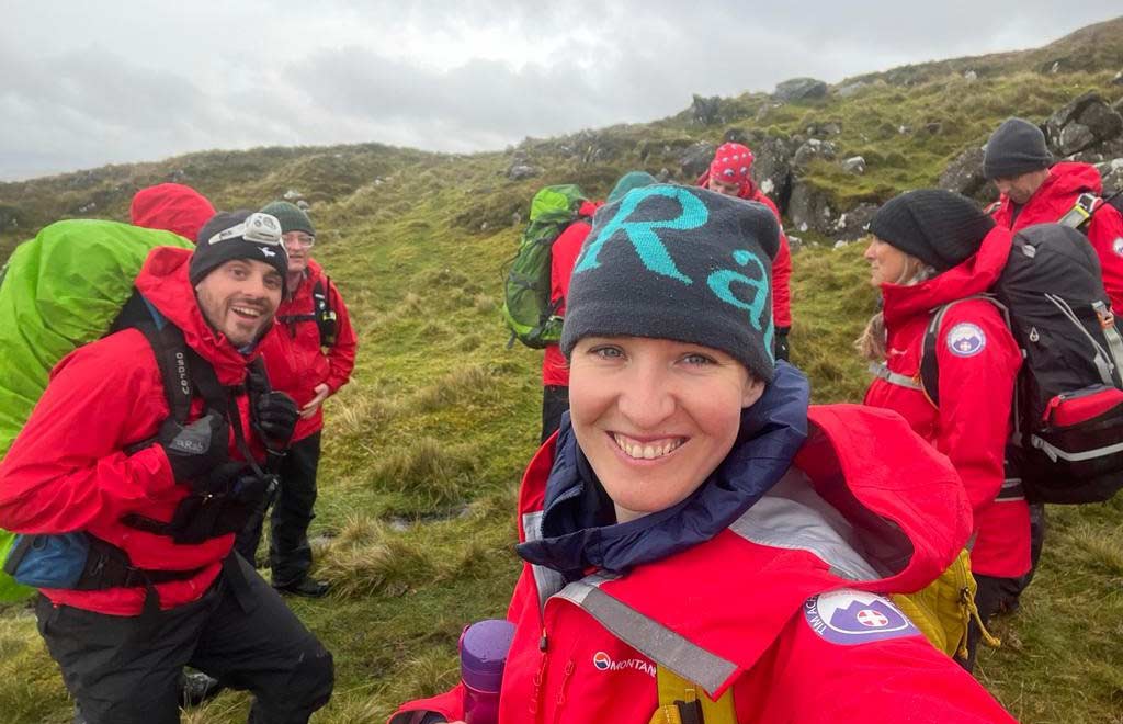 Image of Hayley Jones on top of mountain with men and women in red coats