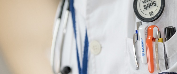 A close-up of a doctor's coat with pens in the pocket