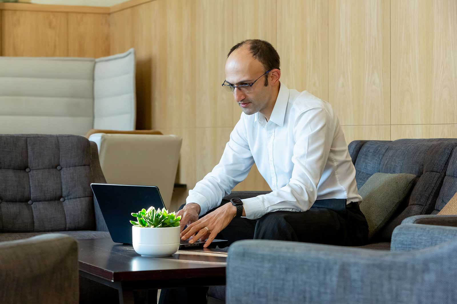 Image of Dr Imran Khan on sofa in white shirt looking at laptop