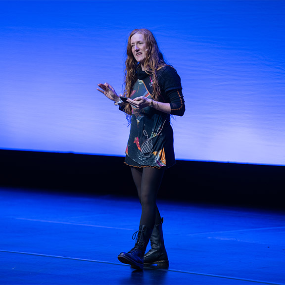 Dr Heidi Phillips stands on a large stage at the RCGP Annual Conference 2024 in Liverpool.