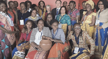A large crowd of smiling men and women wearing traditional dress.