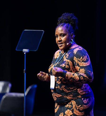 Image of Dr Margaret Ikpoh on stage in front of podium