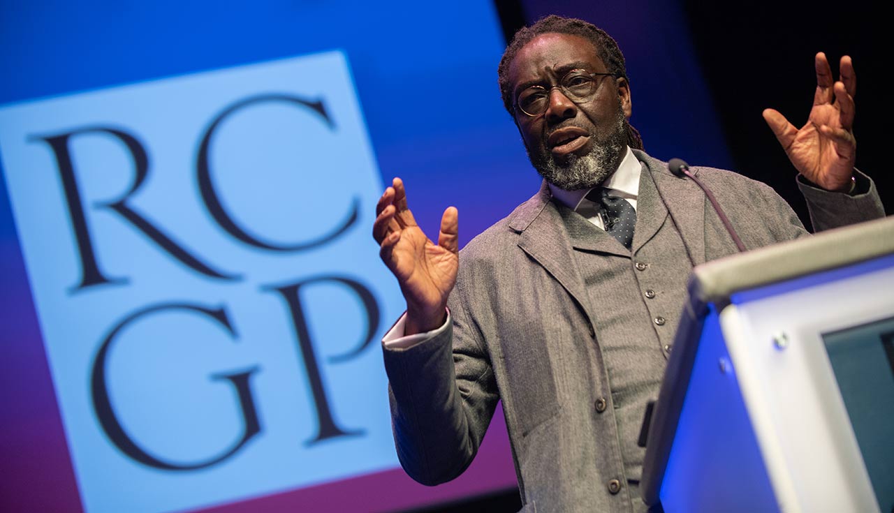 Victor Adebowale stands at a lectern as he addresses the audience, not pictured, at the RCPG Annual Conference.