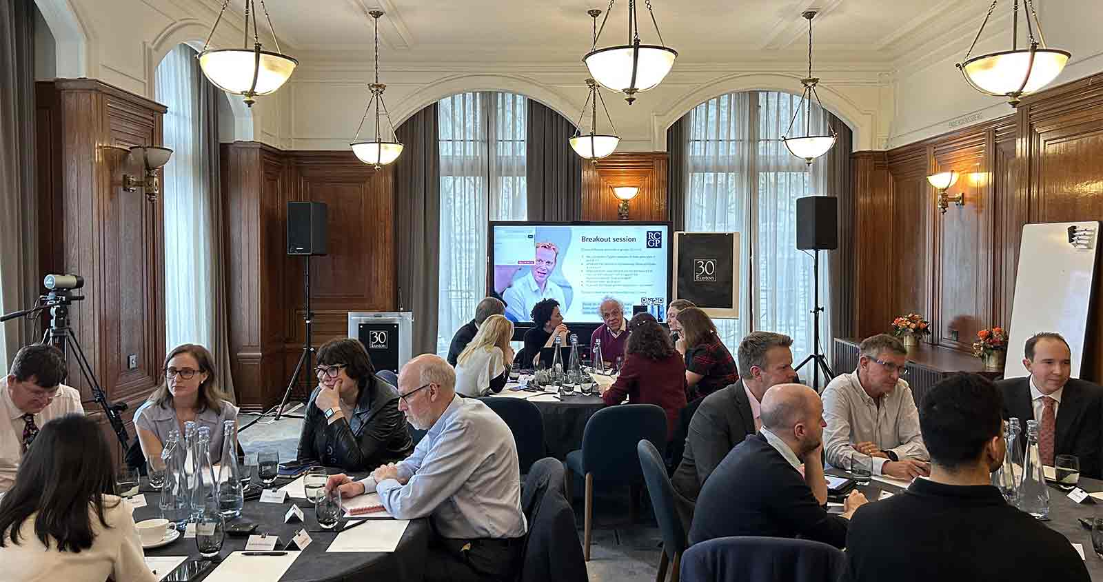 A collection of professionals sit at round tables in conversation.